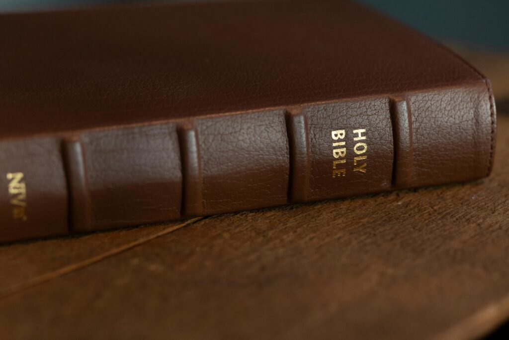 A close-up of a brown leather-bound Holy Bible resting on a wooden surface.